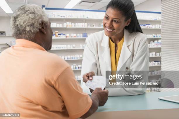 pharmacist handing medication to customer - black pharmacist stock pictures, royalty-free photos & images