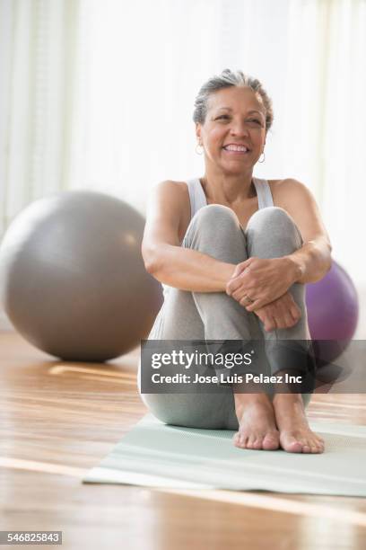 older hispanic woman sitting on exercise mat - fitness ball imagens e fotografias de stock