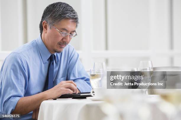 pacific islander businessman using digital tablet at lunch - 2000 teleworking stock pictures, royalty-free photos & images