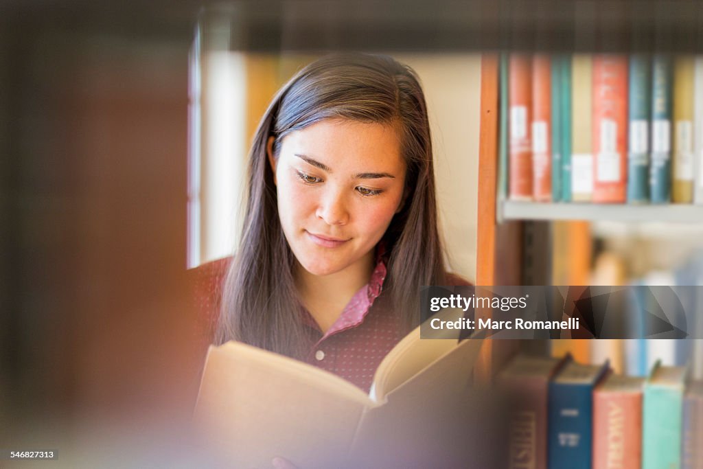 Mixed race student reading in library