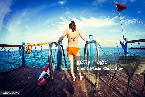 Caucasian girl standing at ladder over ocean Caucasian girl standing at ladder over ocean