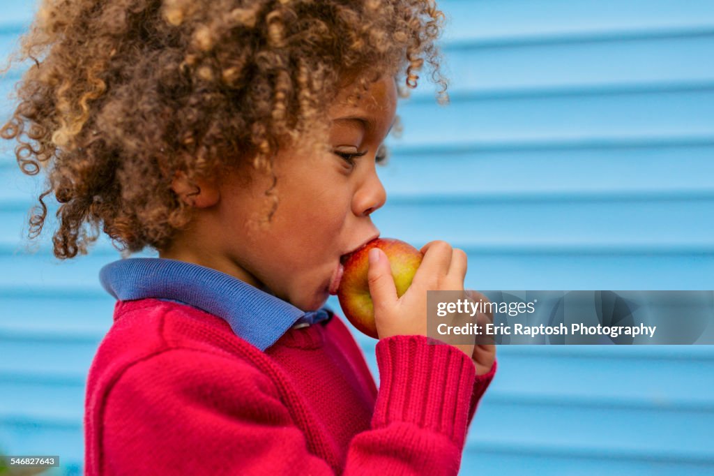 Pacific Islander boy eating apple outdoors