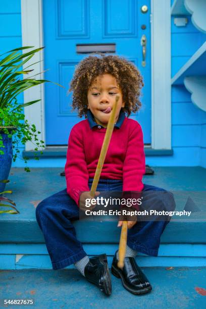 pacific islander boy with drumsticks sitting on front stoop - child prodigy stock-fotos und bilder