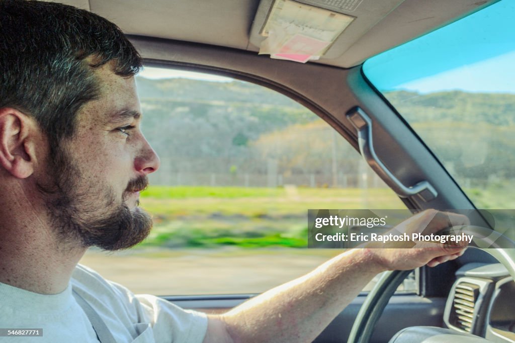 Caucasian man driving car on rural road