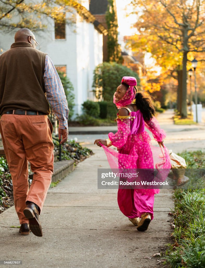 African American girl trick-or-treating with father on Halloween