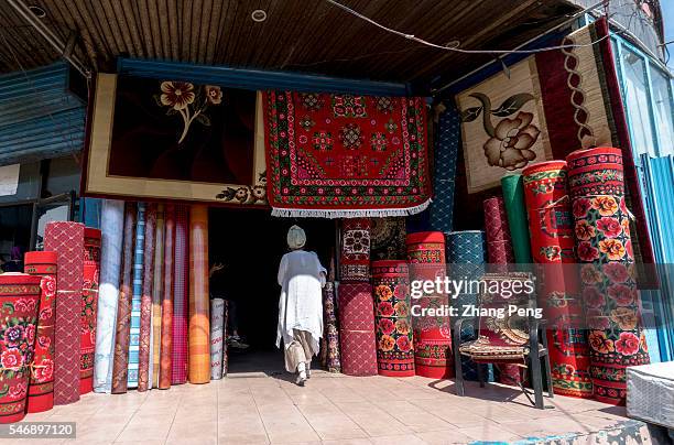 An Uygur woman walks into a traditional carpets shop in the bazaar. Han People street in Yining, the previous dwelling center of Han in the city, is...