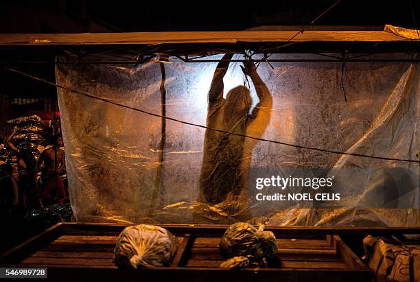 Vegetable vendor arranges a plastic sheet as it is about to rain at the Divisoria market in Manila on July 13, 2016. The Philippines' economy grew a...