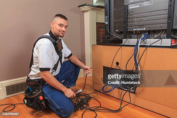 cable installer working in a home behind the tv - cable installer stockfoto's en -beelden