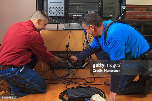 cable installer working with home owner behind tv - cable installer stock pictures, royalty-free photos & images