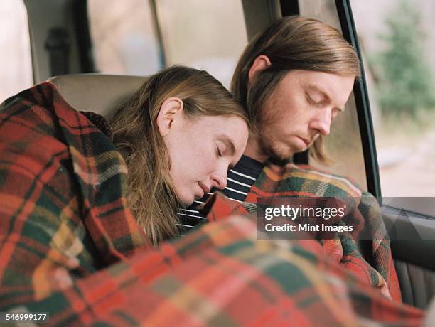 a couple taking a nap in their car, covered by a blanket. - couple sleeping in car stock-fotos und bilder