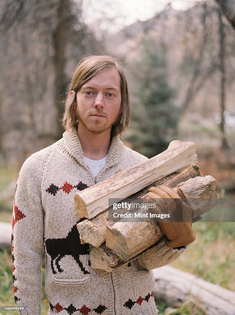 Young blond man carrying firewood.