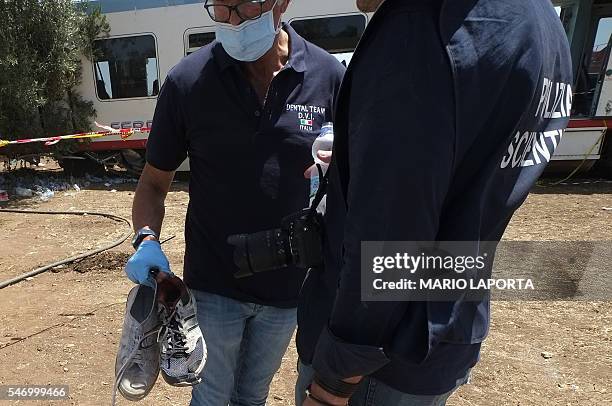 Forensic experts hold shoes of victims of the train crash on July 13, 2016 on the site of the accident near Corato, in the southern Italian region of...