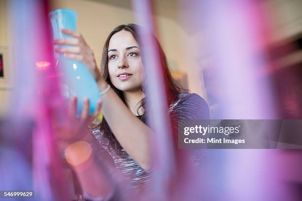 woman holding a blue glass vase. red and pink vases in the foreground. - woodstock new york stockfoto's en -beelden