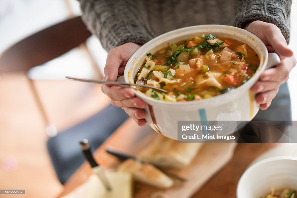 Close up view of a man holding a bowl with a vegetable stew.