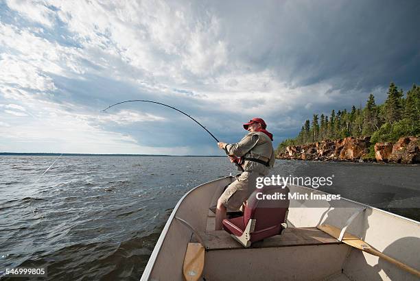 a man fishing from an open boat offshore. a fish on the line. the fishing rod bending from the weight. - deep sea fishing stock pictures, royalty-free photos & images