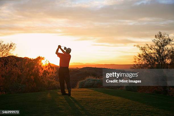 golfer teeing off into the sunset on the golf course. - arizona golf stock pictures, royalty-free photos & images