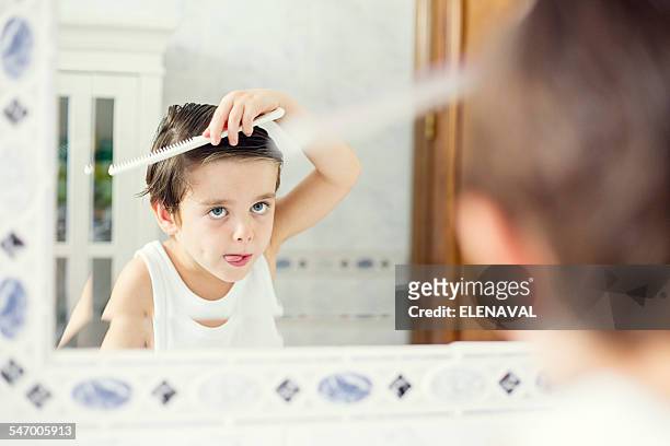 boy standing in front of a mirror combing his hair - combing stock pictures, royalty-free photos & images