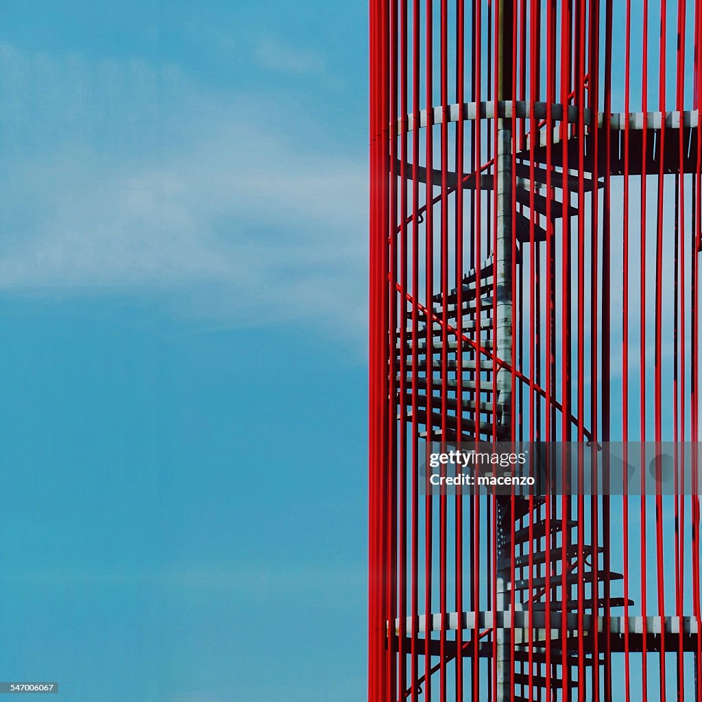 Close-up of red metal staircase against blue sky