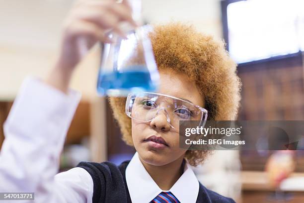 head and shoulders shot of mixed race female student looking at content of volumetric flask, cape town, south africa - explicit content stock pictures, royalty-free photos & images