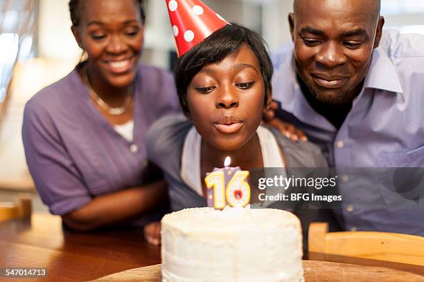 african female teenager blowing out the candles on her 16th birthday cake, surrounded by her family , cape town, south africa - 16th birthday - fotografias e filmes do acervo