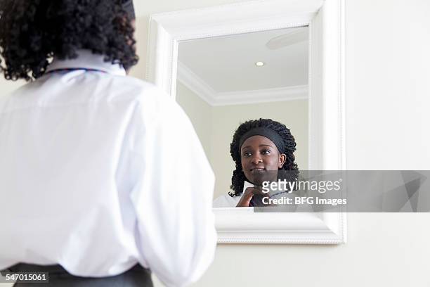 african female teenaged student doing her school tie in the mirror, cape town, south africa - girl in mirror stock pictures, royalty-free photos & images