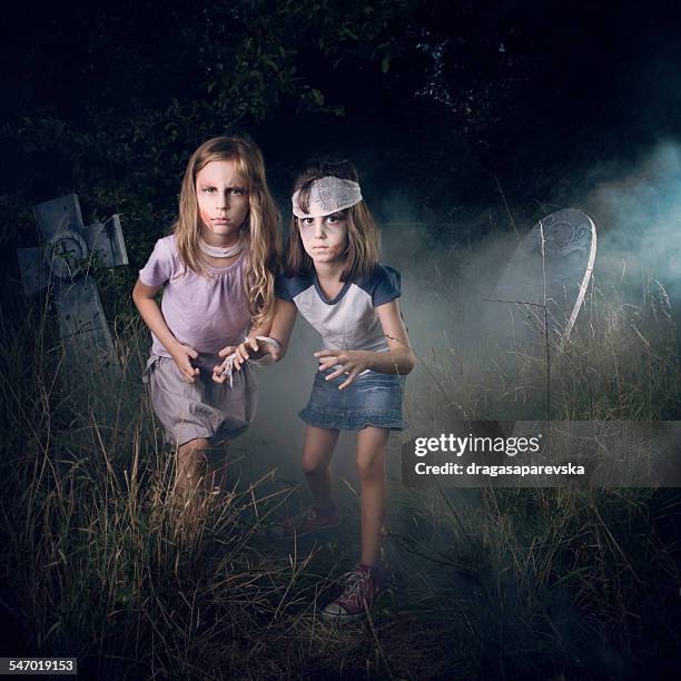 two girls pretending to be zombies in a cemetery at halloween - zombie girl ストックフォトと画像