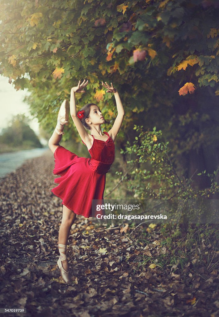 Girl doing ballet outdoors in red dress