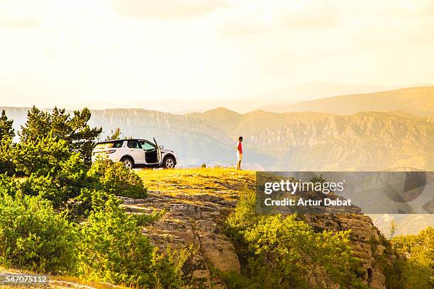 adventure guy traveling around the pyrenees mountains driving with suv car to the top of the mountains with nice views on sunset. - summer vibe stockfoto's en -beelden