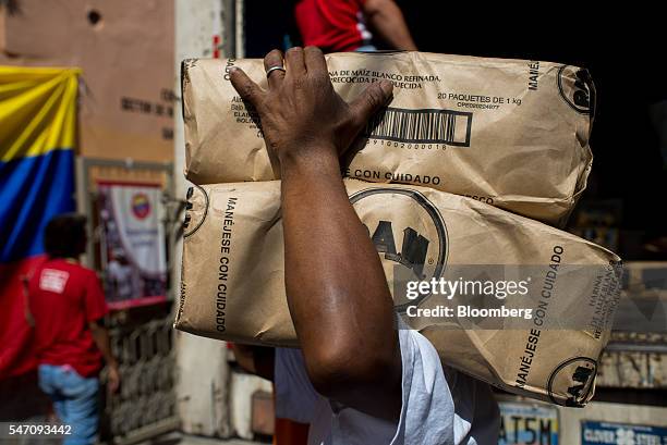 CLAPs member carries packets of corn flour in the Catia neighborhood on the outskirts of Caracas, Venezuela, on Saturday, July 2, 2016. In an attempt...