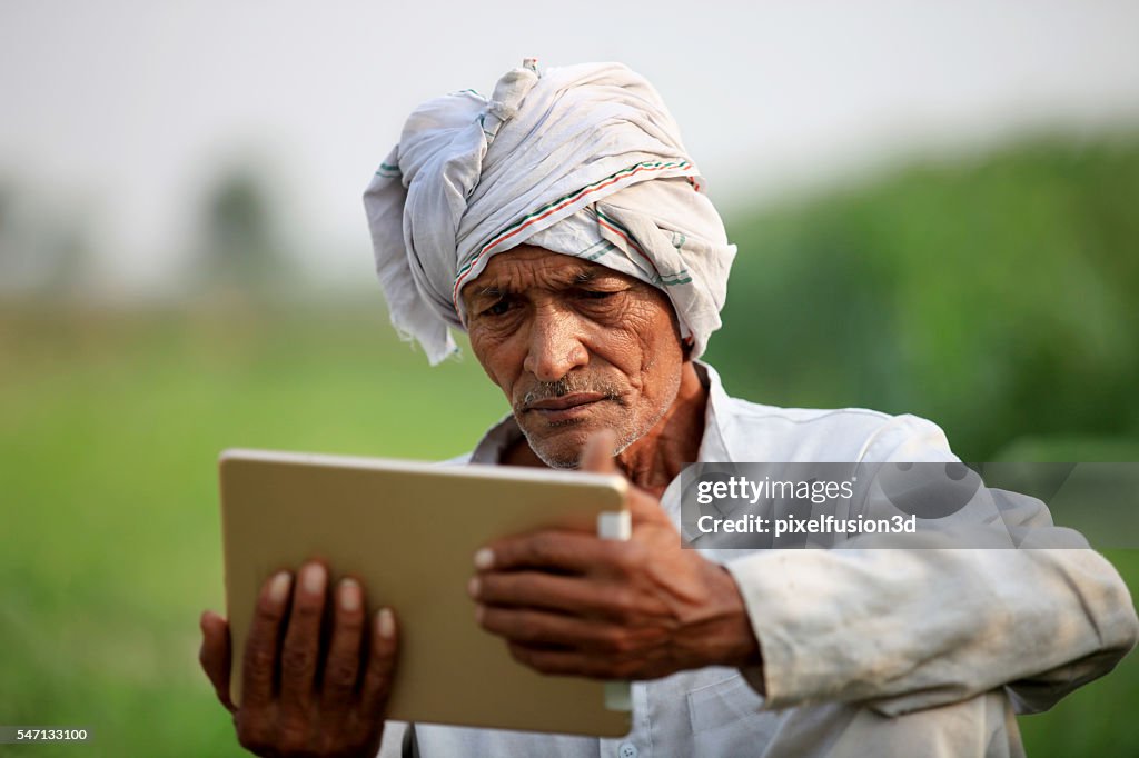 Old farmer holding digital tablet