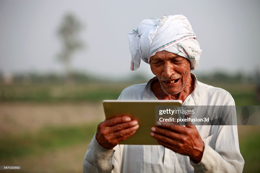 Happy  Old farmer holding digital tablet