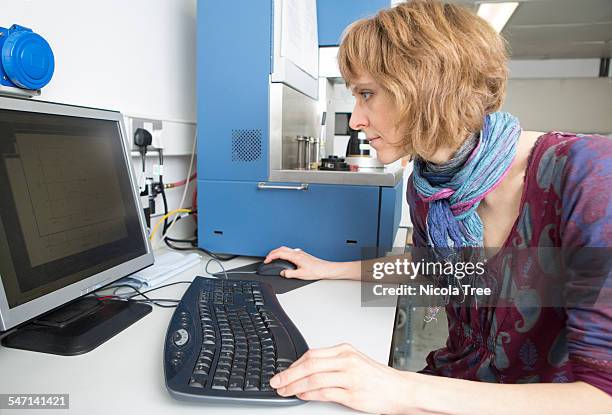 female chemical engineer analysing computer data - bata de laboratório - fotografias e filmes do acervo