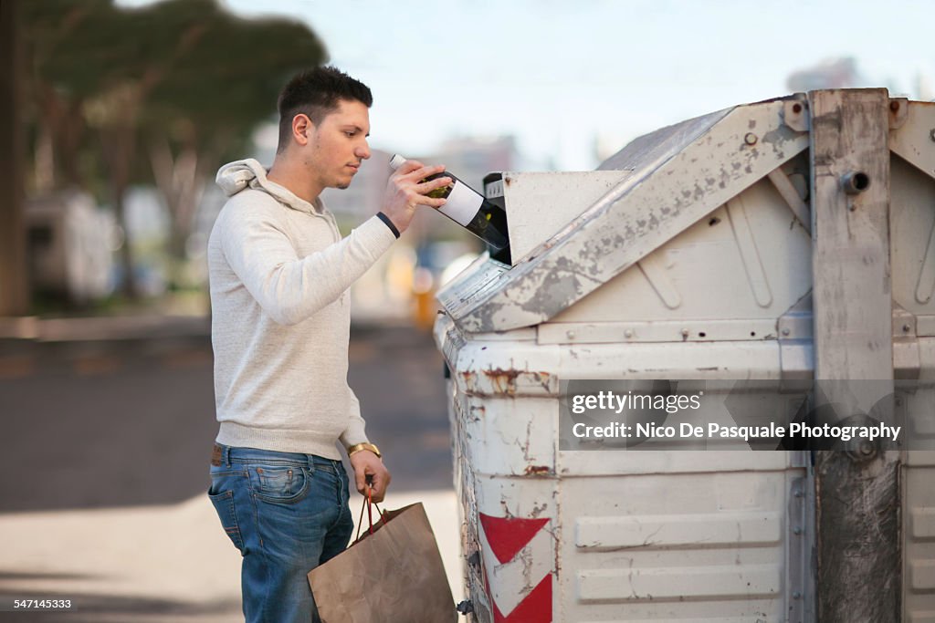 Young man recycling glass bottle