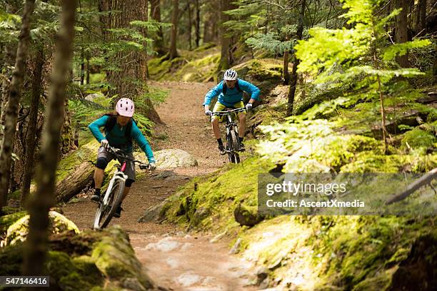 couple mountain biking through a forest - cross country cycling stock pictures, royalty-free photos & images