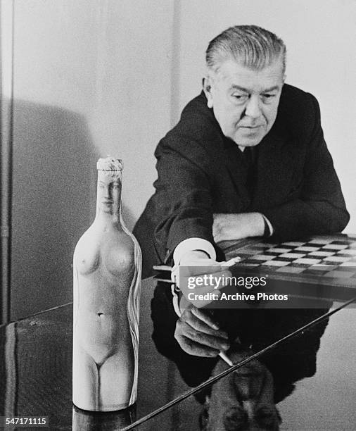 Belgian surrealist artist Rene Magritte with 'Femme-Bouteille', his oil painting of a nude on a glass bottle, circa 1955.