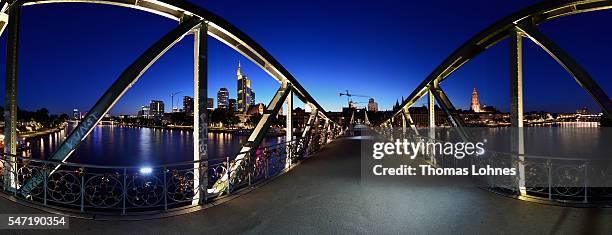 The bridge 'Eiserner Steg' and the skyline of Frankfurt with the skyscrapers illuminated at night pictured on June 26, 2016 in Frankfurt, Germany....