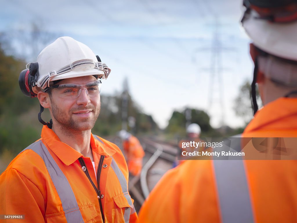 Portrait of apprentice railway maintenance worker in discussion on track