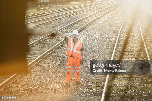 railway worker signalling to train on railway - monty shadow stockfoto's en -beelden