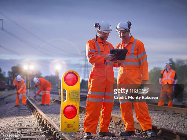 railway maintenance workers using digital tablet at night - uniform werk stockfoto's en -beelden