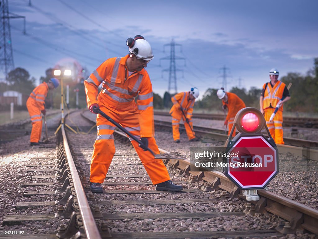 Railway maintenance workers on track with stop sign at night