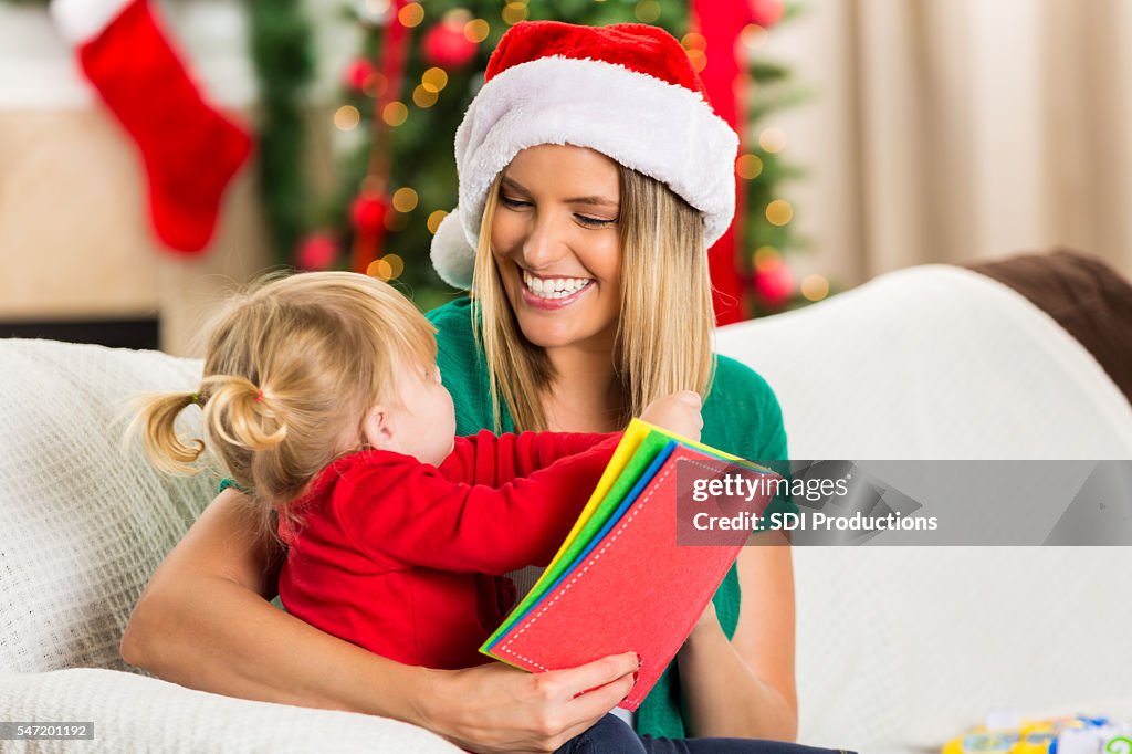 ママと幼児の娘はクリスマスに本を読む