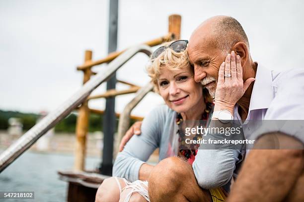 senior couple sitting on the jetty relaxing - jetty stock pictures, royalty-free photos & images