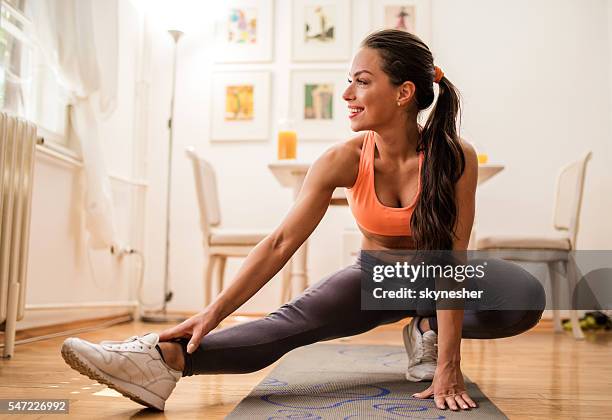 young smiling woman warming up and stretching her legs. - warming up for exercise stock pictures, royalty-free photos & images