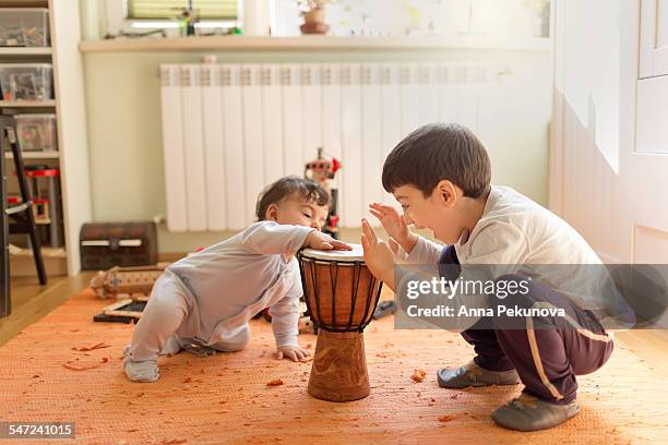 siblings playing at djembe (african drum) - djembe foto e immagini stock