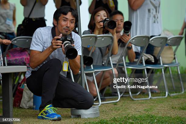 Former Olympian Dai Tamesue with a camera looks on during his track and field class for children 'Tamesue College Running Club' at Toyosu MAGIC BEACH...