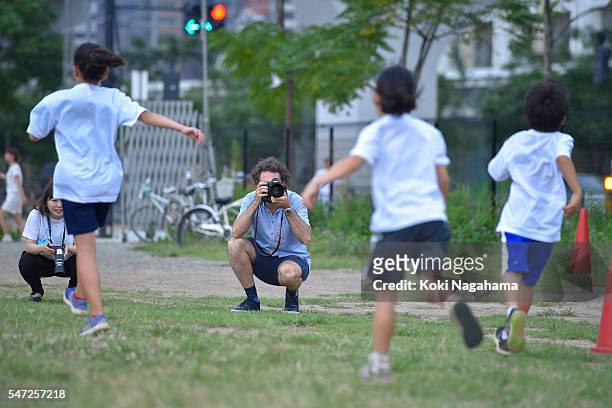 Getty Images photographer Adam Pretty takes photographs during his track and field class for children 'Tamesue College Running Club' at Toyosu MAGIC...