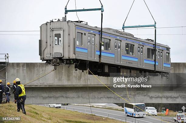 Japan - A train car is lifted by crane in Higashimatsushima, Miyagi Prefecture, in northeastern Japan, on Dec. 8 to be loaded onto a trailer. East...