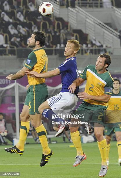 Qatar - Japan's Keisuke Honda is caught between Australia's Sasa Ognenovski and Lucas Neill as Honda jumps into a cross during the first half of the...