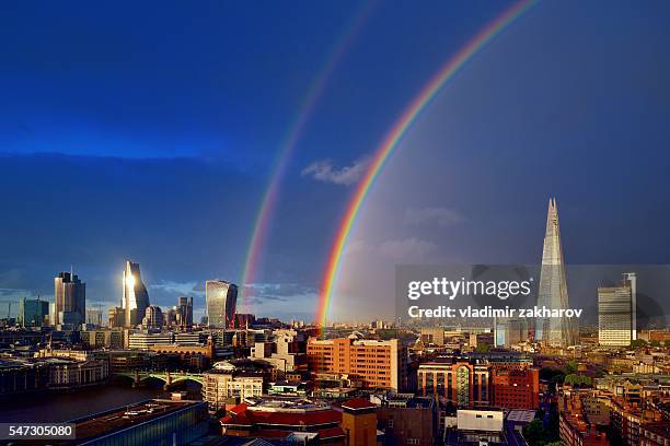 london cityscape after rain with double rainbow in dark sky - sunset on canary wharf stock-fotos und bilder