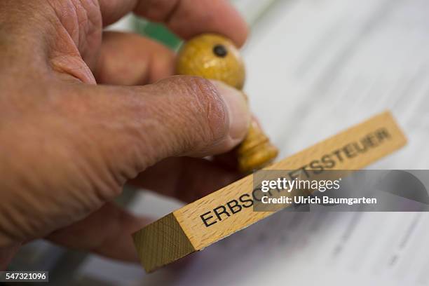 Inheritance tax. Hand holding a stamp with the inscription inheritance tax.